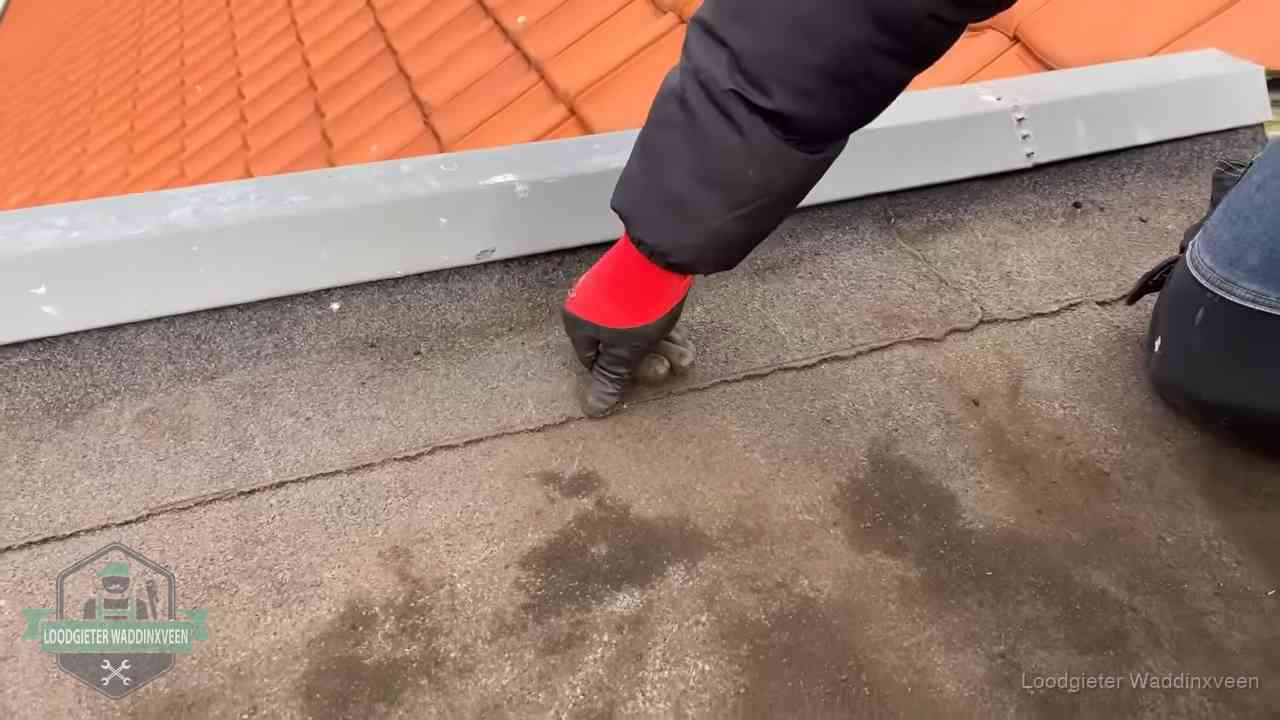 Lekkage bij de naad van een plat dak in Waddinxveen Vakman wijst een naad met vochtplekken aan op een bitumen plat dak in Waddinxveen