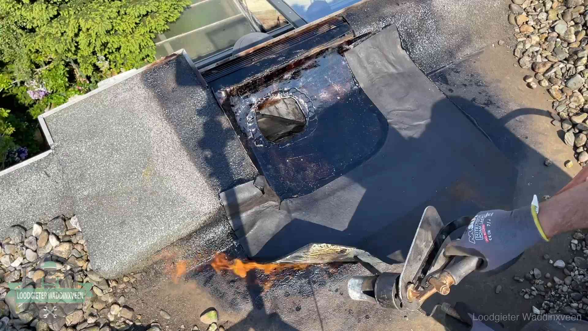 Daklekkage repareren in Waddinxveen Dakdekker brandt bitumen rond een doorvoer tijdens een daklekkage-reparatie in Waddinxveen