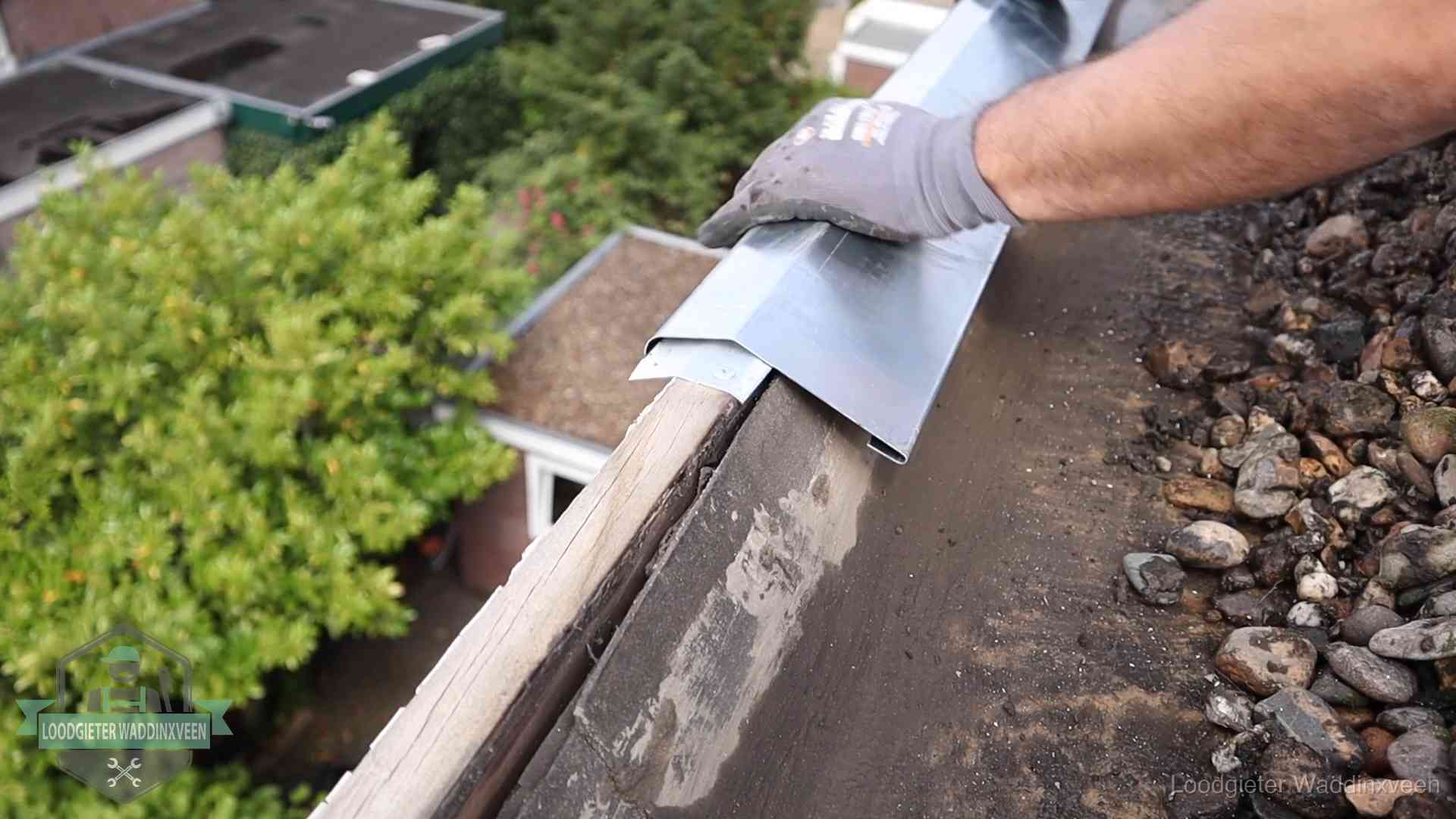 Daklekkage per wijk in Waddinxveen Dakdekker plaatst een zinken deklijst op een dakrand met uitzicht over een woonwijk in Waddinxveen