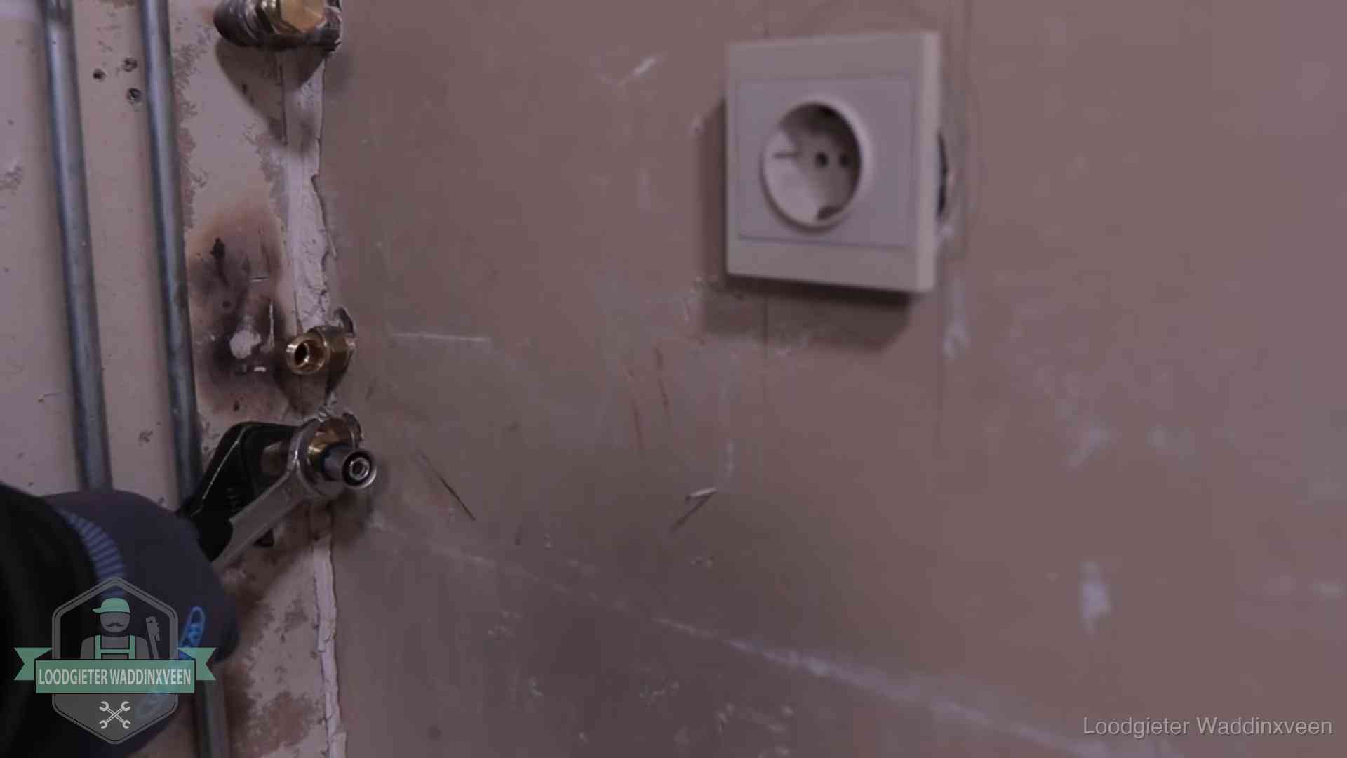 Monteur draait een perskoppeling vast op een leidingaansluiting in Waddinxveen