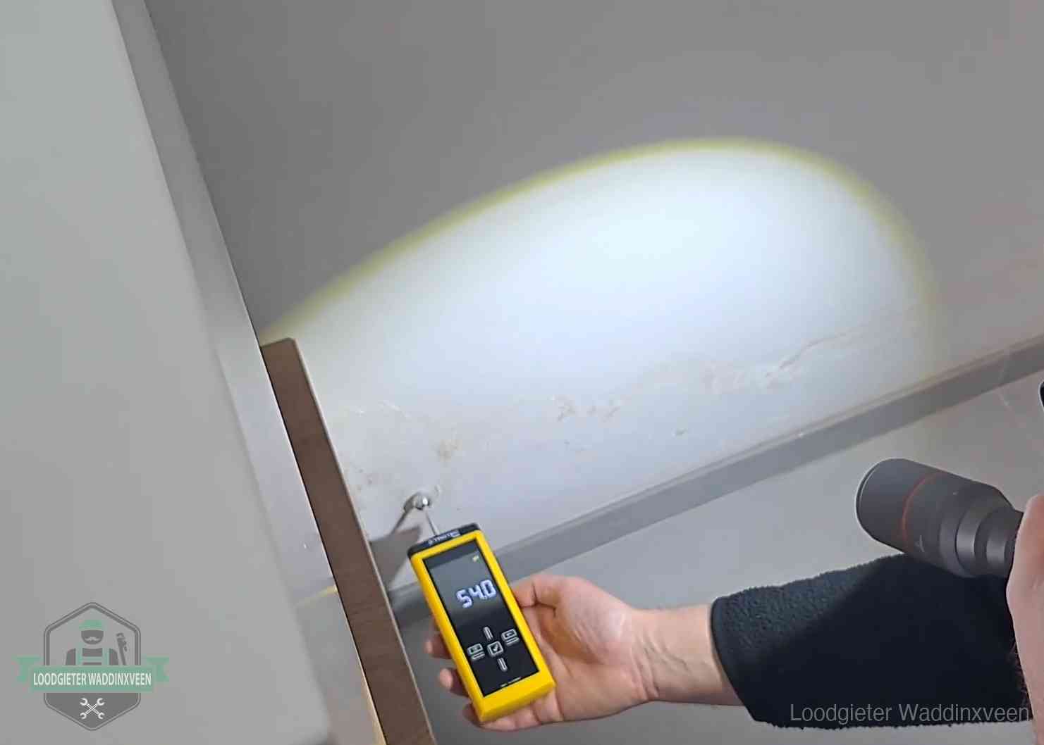 Vochtmeter tegen een natte wand met lekkagesporen in Waddinxveen