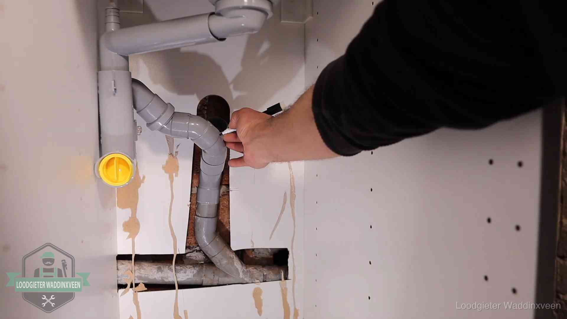 Loodgieter markeert een pvc-afvoerbuis onder een gootsteen in Waddinxveen