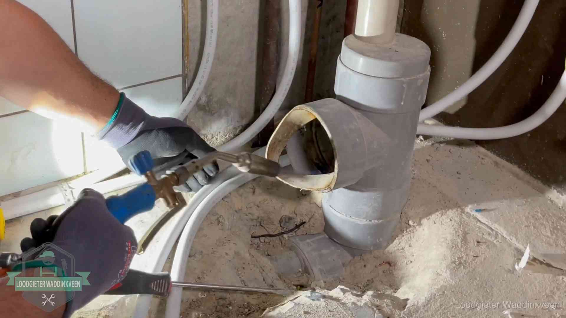 Loodgieter werkt met brander en messing kraanwerk aan leidingen in Waddinxveen