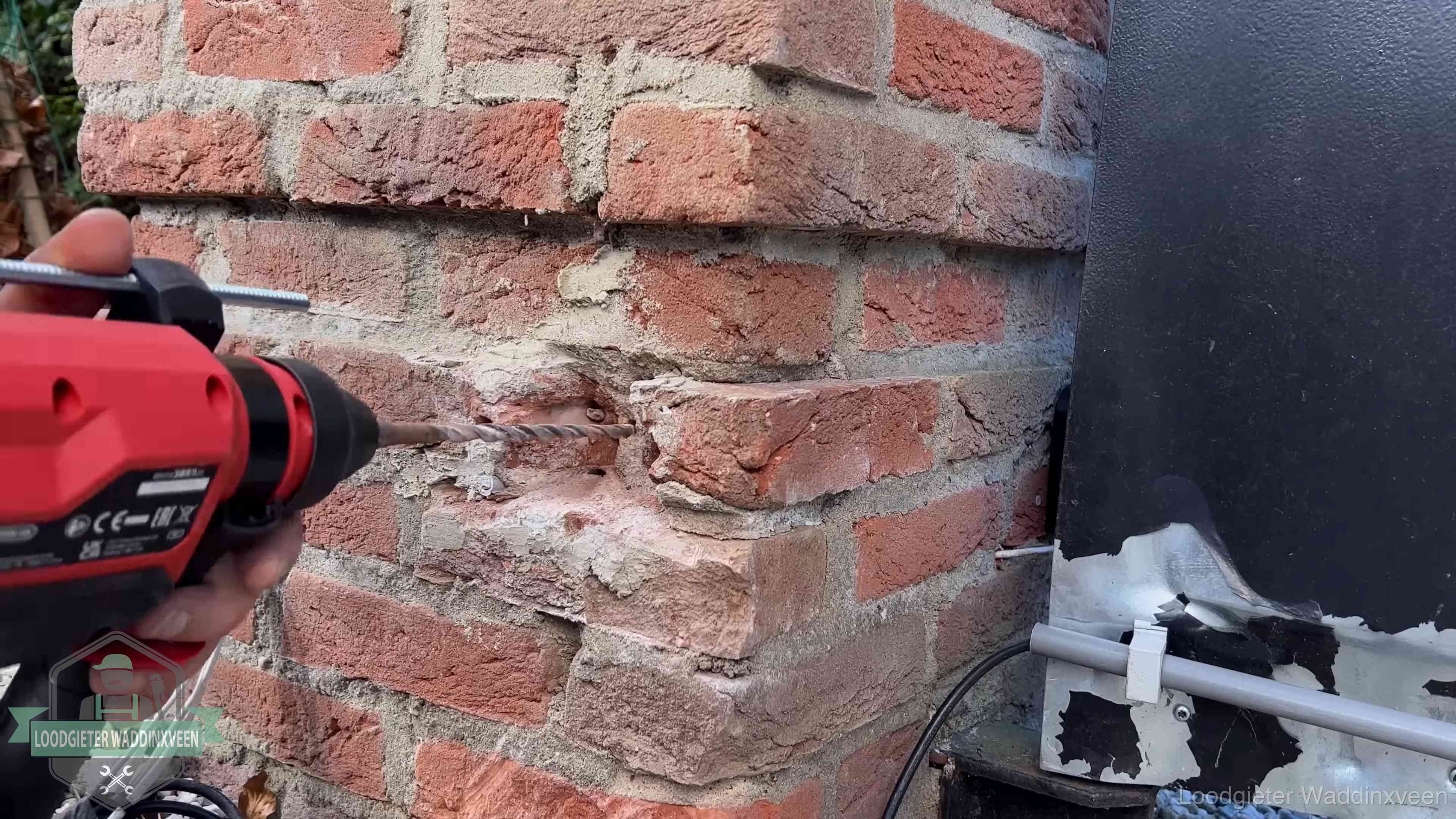 Vakman boort in de buitenmuur van een woning in de regio Waddinxveen