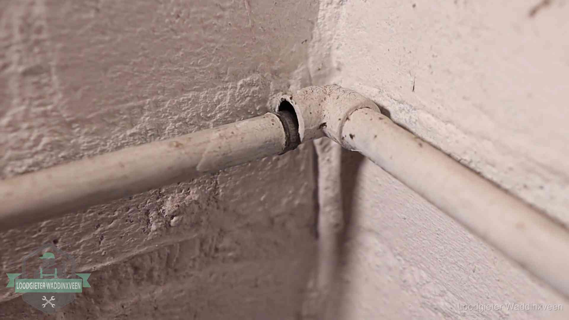 Oude geverfde waterleiding met een losliggende fitting in een woning in Waddinxveen