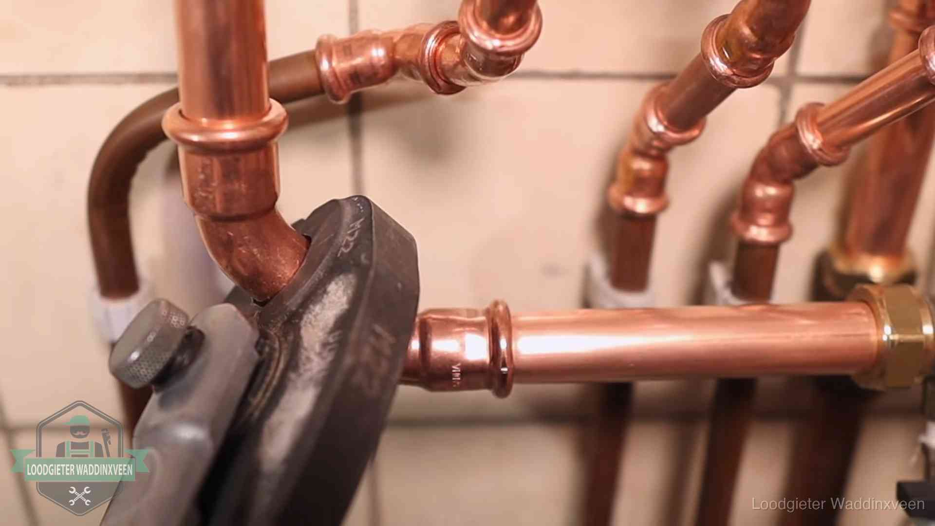 Persmachine perst een koperen fitting op nieuw leidingwerk in Waddinxveen