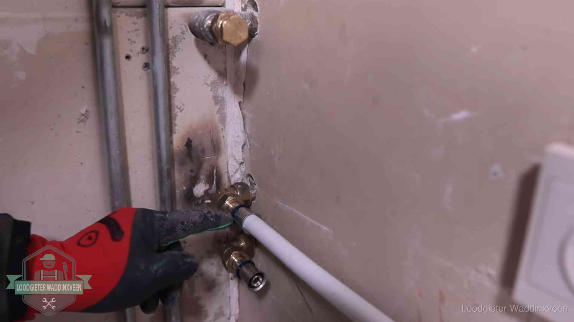 Loodgieter wijst de persfitting op nieuwe muuraansluitingen aan in een woning in Waddinxveen
