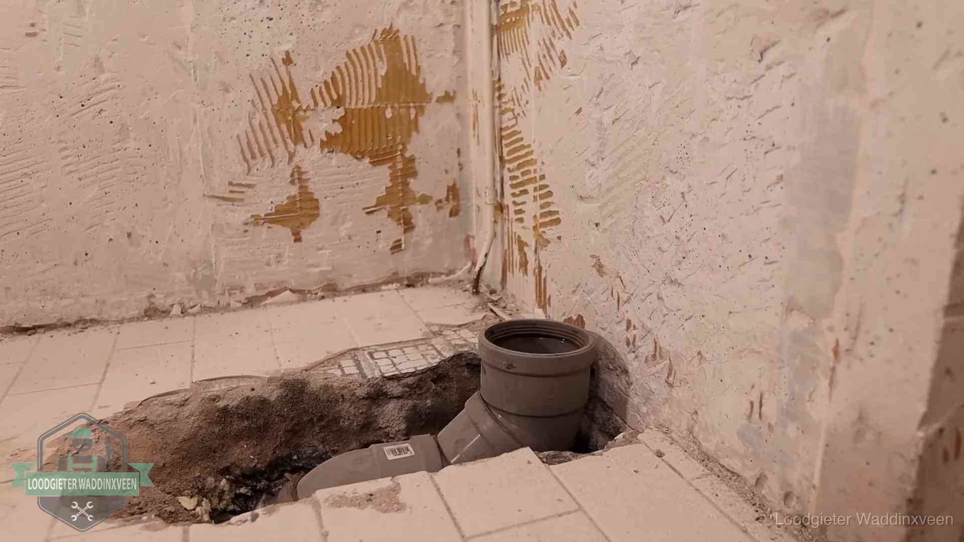Verzakt riool herstellen in Waddinxveen Opengebroken vloer met een nieuwe pvc-rioolbocht in een gegraven sleuf in Waddinxveen